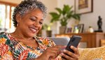 Smiling South African woman over 50 writing her online dating profile on her phone